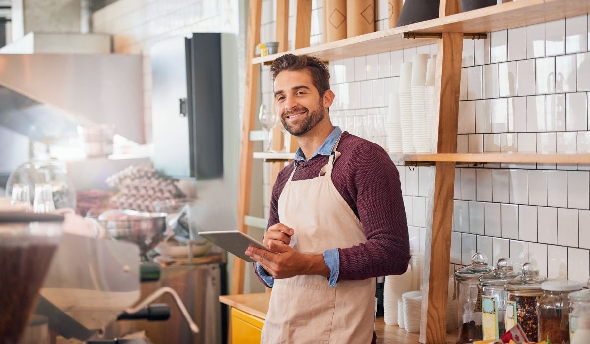 male business owner smiling while holding tablet
