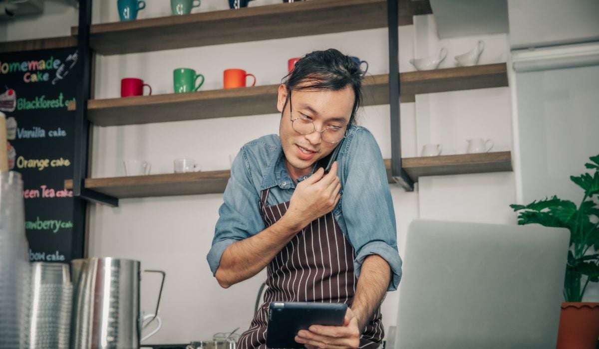 business owner man on phone while looking at tablet