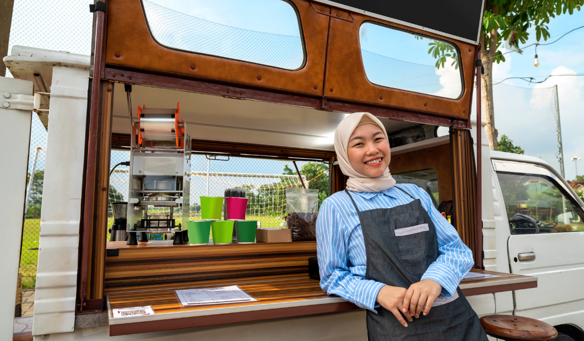 woman leaning against food truck and smiling