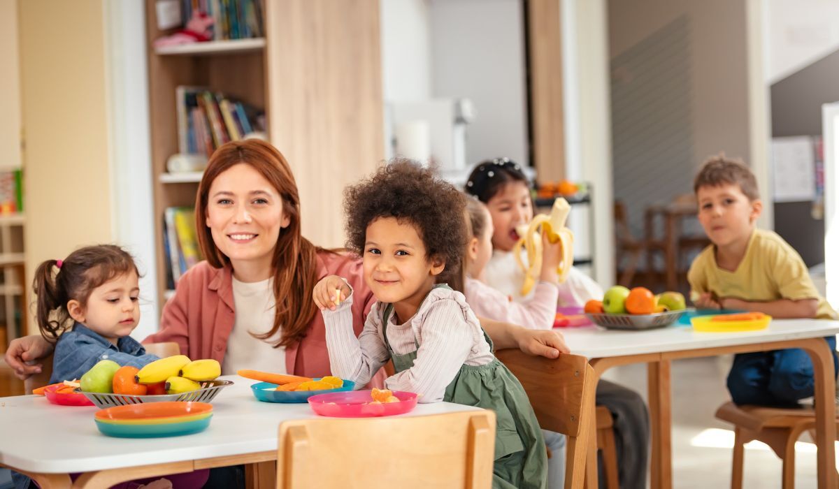 female daycare owner sitting at small table with two toddlers